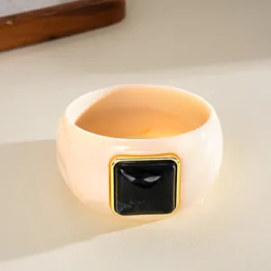 Detailed macro view of a retro acrylic bangle with black square inlay and gold trim