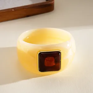 Detail view of a retro cream acrylic bangle with a square tortoise-shell pattern inlay