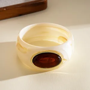 Detailed view of a vintage cream marble acrylic bangle with amber resin oval stone
