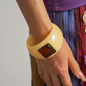 Detailed close-up of retro cream acrylic bangle with square amber stone on a model's wrist