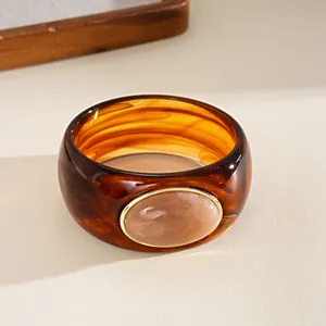 Macro detail of a vintage tortoiseshell acrylic bangle with an oval stone inlay.