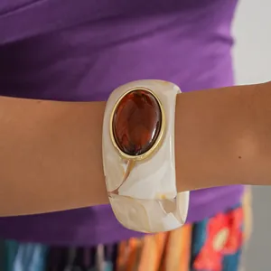 Detail view of a retro acrylic bangle with marble pattern and an amber resin stone inlay.