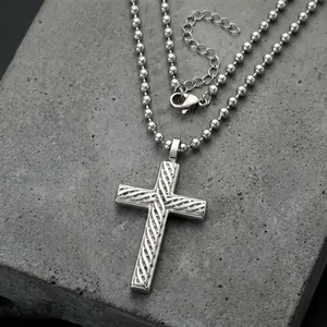 Macro view of stainless steel cross pendant with twisted texture on bead chain