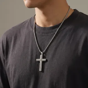 Detailed view of masculine stainless steel cross pendant with twill texture on a box chain