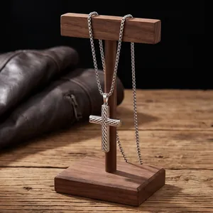 Detailed close-up of a silver stainless steel cross pendant with twill texture on a stand