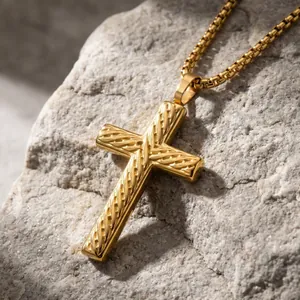 Close-up of gold stainless steel cross pendant with diagonal textured patterns