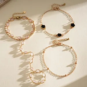 Macro view of elegant golden resin oval hand chain and black clover charm bracelets.