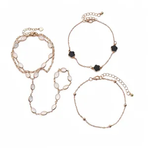 Set of gold-tone bracelets featuring quatrefoil charms and oval resin stones on white