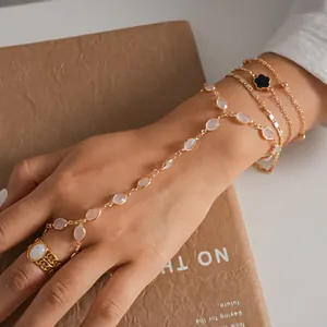 Detailed close-up of gold hand harness with white oval resin beads and black charm
