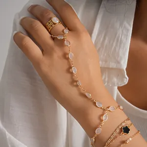 Detailed view of gold metal hand chain with oval resin beads and black flower charm