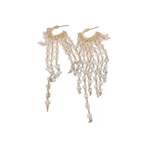 Elegant gold huggie hoop earrings with long clear crystal bead tassels on white background