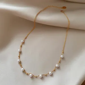 Elegant 18k gold plated necklace with delicate white pearls on a silk background