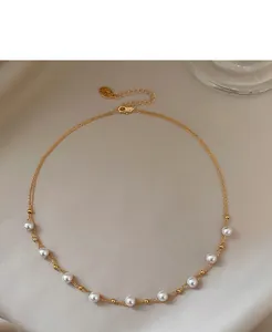 Detail of a double-strand 18k gold plated necklace featuring elegant white pearls.