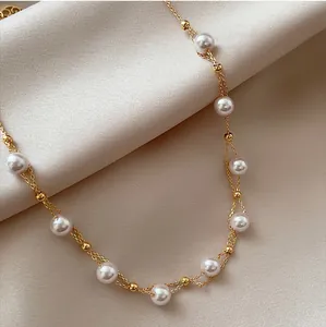 Elegant double-layered 18k gold plated pearl necklace detail view on soft beige silk background.