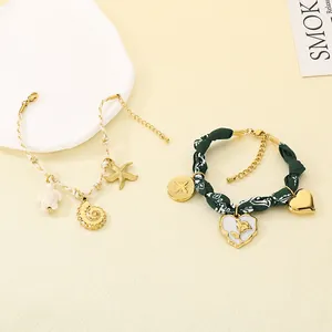 Detail view of summer ocean style rope and floral fabric bracelets with conch pendants