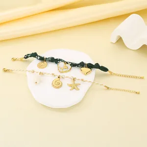 Detailed close-up of summer floral fabric and braided nautical charm bracelets on white stone
