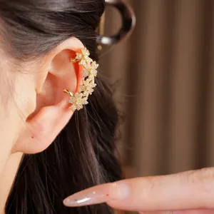 Detail van 14k vergulde bloemen ear cuff met sprankelende zirkoon op het oor.