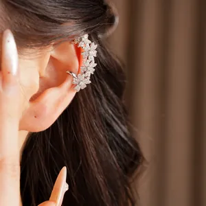 Detailopname van een delicate 14k vergulde zirkoon bloem oorklem gedragen door een model