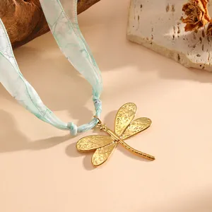Close-up of golden dragonfly pendant on a mint green silk ribbon necklace