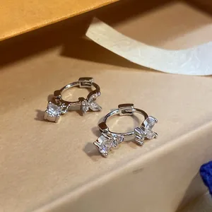 Detailed view of silver-finish hoop earrings featuring zircon butterfly and square charms