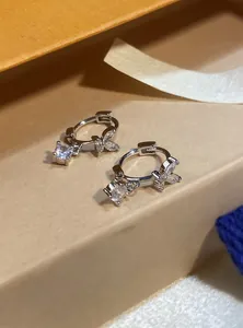 Detailed macro view of silver butterfly hoop earrings with sparkling round zircon pendants.