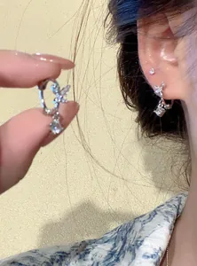 Close-up of elegant zircon butterfly hoop earrings with sparkling square pendant on ear