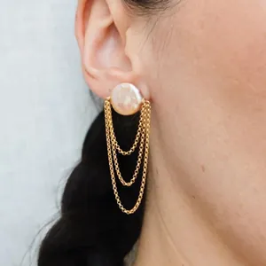 Close-up van zoetwaterparel oorbellen met hangende gouden ketting franjes