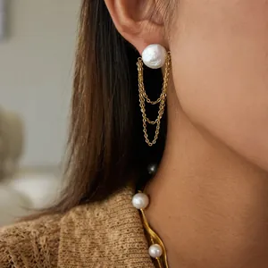 Detailopname van luxe pareloorknopjes met drievoudige gouden kettingen op een model