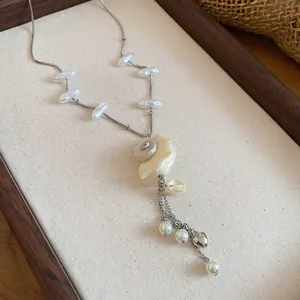 Detailed view of a conch shell and pearl pendant necklace designed for beach vacation sets.