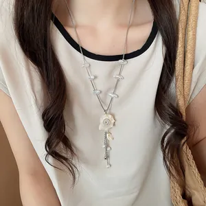 Detail of beach-style necklace featuring natural shells and pearls on a model