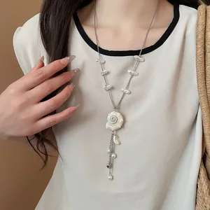 Detail of a conch and pearl tassel necklace for summer beach vacation outfits.