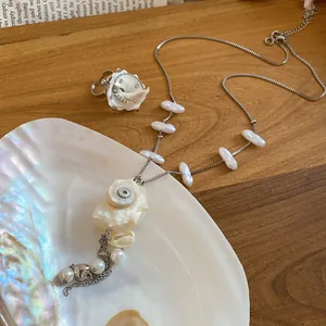 Detailed close-up of an elegant shell and pearl necklace and ring set for beach vacations.
