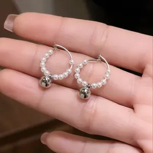 Macro view of French style silver hoop earrings with white pearls and metal ball