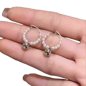 French style beaded pearl hoop earrings with silver metallic ball charm held by hand