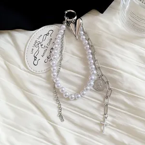 Detail view of a stylish pearl and chain keychain featuring heart and cross charms.