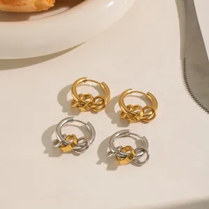Dettaglio di orecchini minimalisti in acciaio inox con anelli intrecciati oro e argento