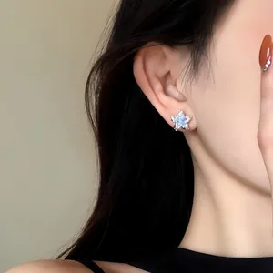 Close-up of a sparkling crystal star stud earring worn on an ear for a sweet look