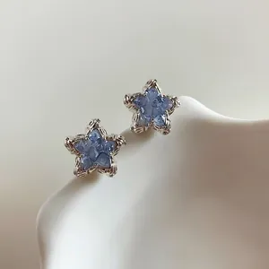 Close-up of sparkling light blue crystal star stud earrings with silver-toned frames