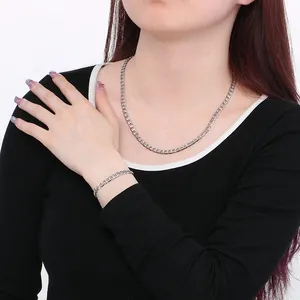 Close-up of a stylish silver stainless steel curb chain necklace and bracelet on a model.