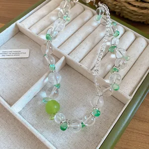 Primo piano di una collana di perle di cristallo con ciondolo a frutto verde in vassoio
