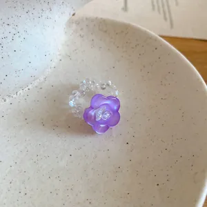 Dettaglio macro di un anello a fiore viola con fascia di perle di cristallo iridato