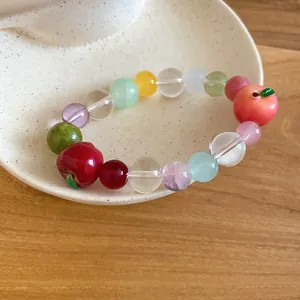 Primo piano di un braccialetto di perline di cristallo con due ciondoli a forma di mela.
