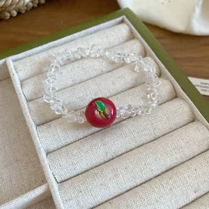 Dettaglio del braccialetto con perline di cristallo e ciondolo mela in una scatola verde