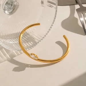 Macro-opgave van een elegante 18K vergulde roestvrijstalen open manchetarmband met marquise steen.