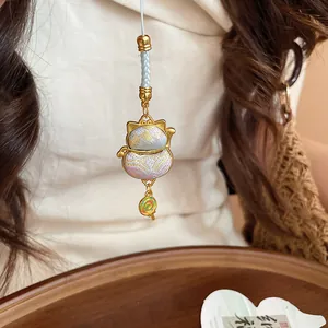 Detailed view of lucky bag cat pendant with woven texture and a lollipop charm