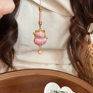 Detailed view of pink embroidered lucky cat charm with gold cat paw dangle
