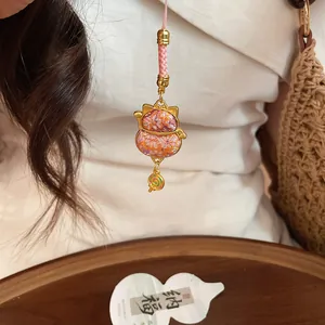 Close-up of an embroidered lucky cat charm featuring a cute lollipop pendant detail