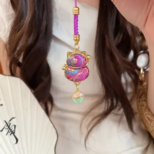 Close-up of a purple embroidered Maneki-neko lucky bag pendant with gold accents