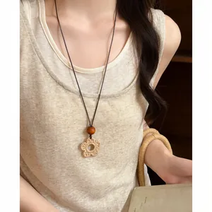 Close-up of a vintage ethnic woven long necklace with a bohemian flower pendant.