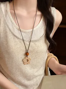 Detailed view of a Bohemian woven flower long necklace on a model wearing cream top
